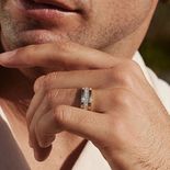A man wearing a thick band with a ring of stones in the center.
